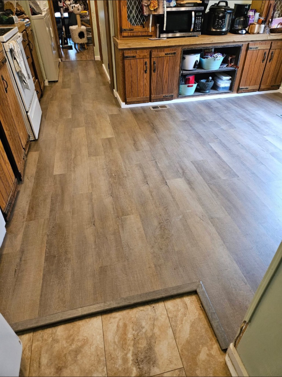 Plank flooring through a kitchen with a tile transition
